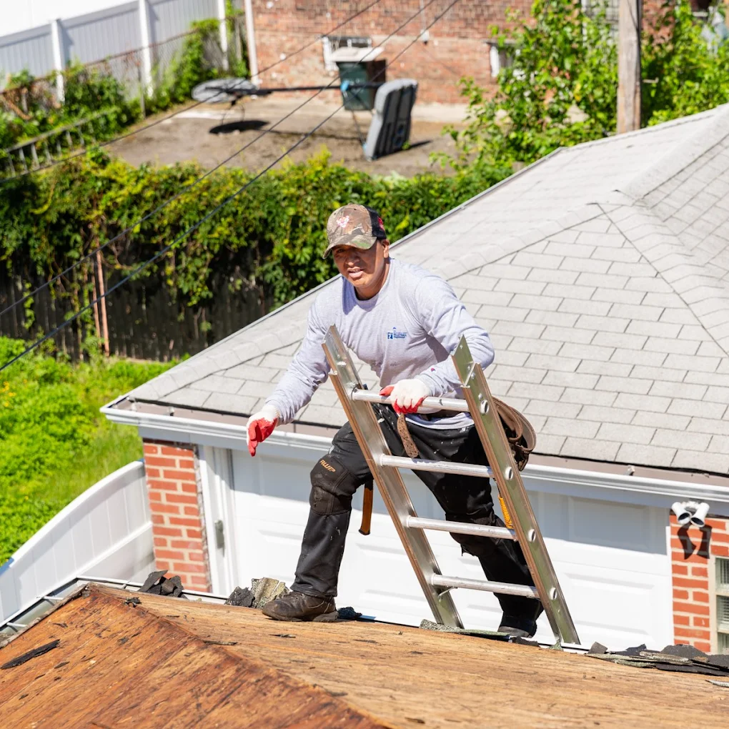 Roofer climbing a ladder onto a residential rooftop, using safety gear and tools to perform professional roofing services.
